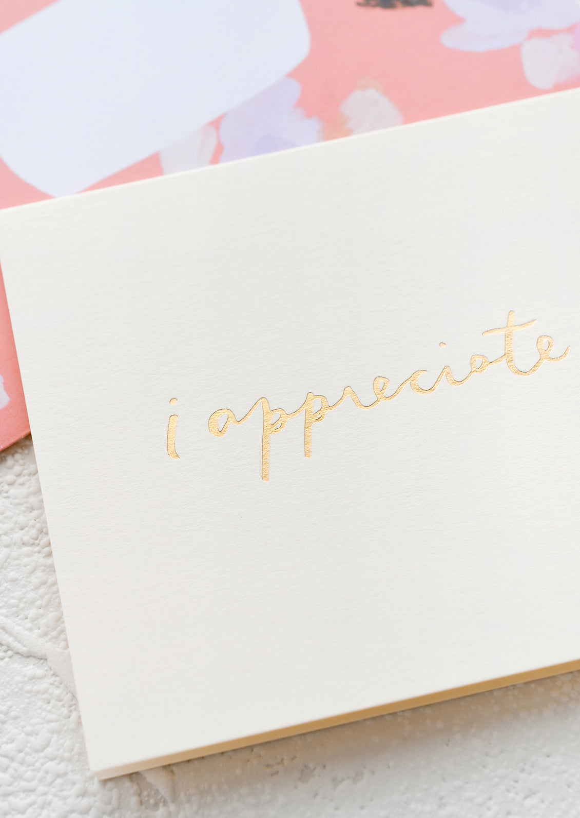 A white greeting card with golden cursive reading "I Appreciate You".