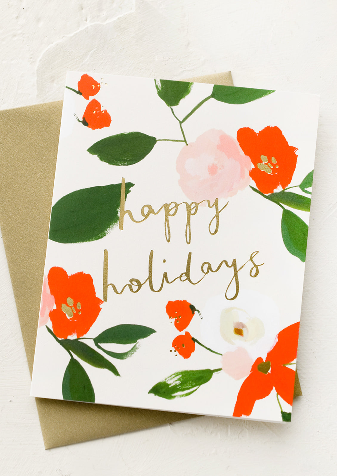 A red and green floral print greeting card with "Happy holidays" in gold script.
