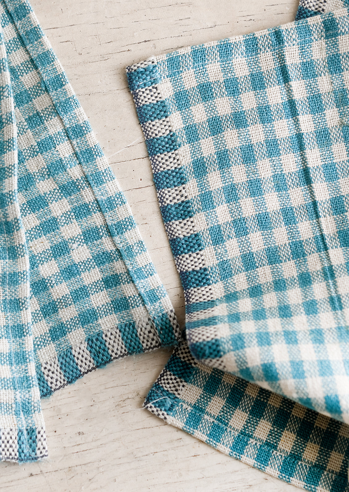 A pair of turquoise gingham cocktail napkins.