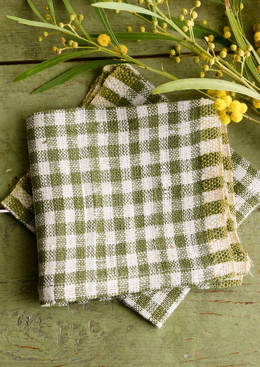 A pair of olive green gingham cocktail napkins.