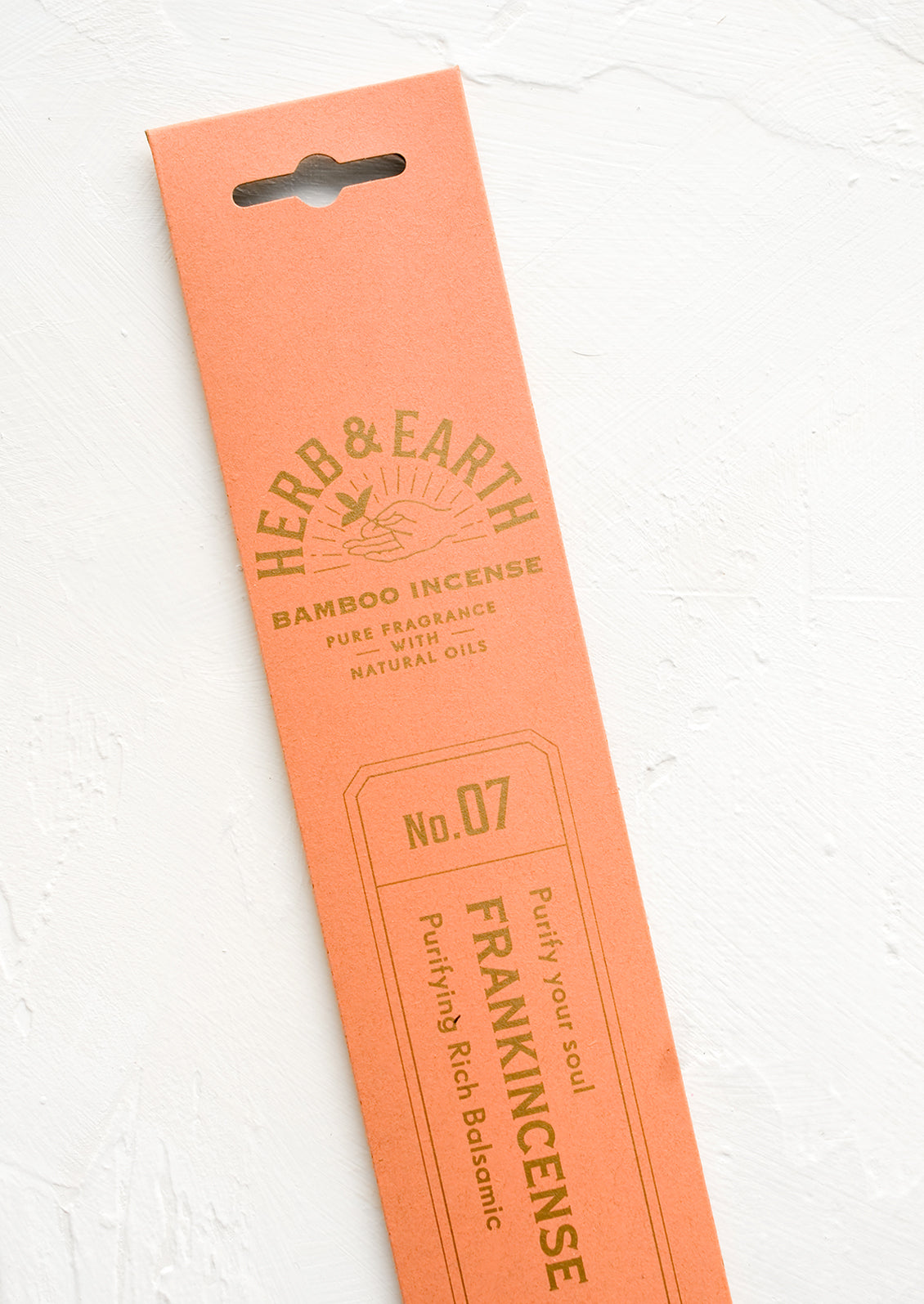 A salmon pink packaging sleeve containing frankincense scented incense.