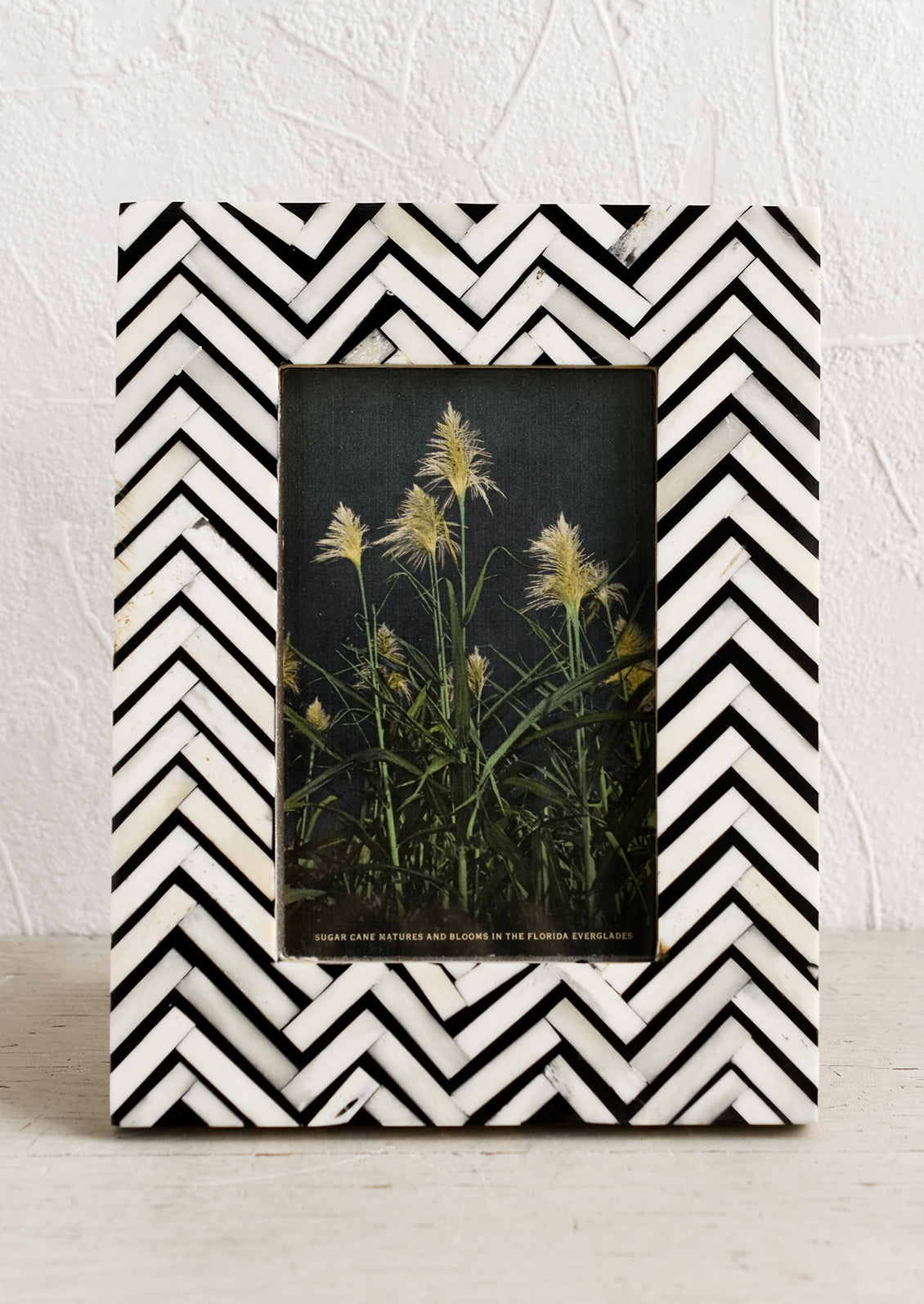 A bone picture frame with black and white chevron pattern.
