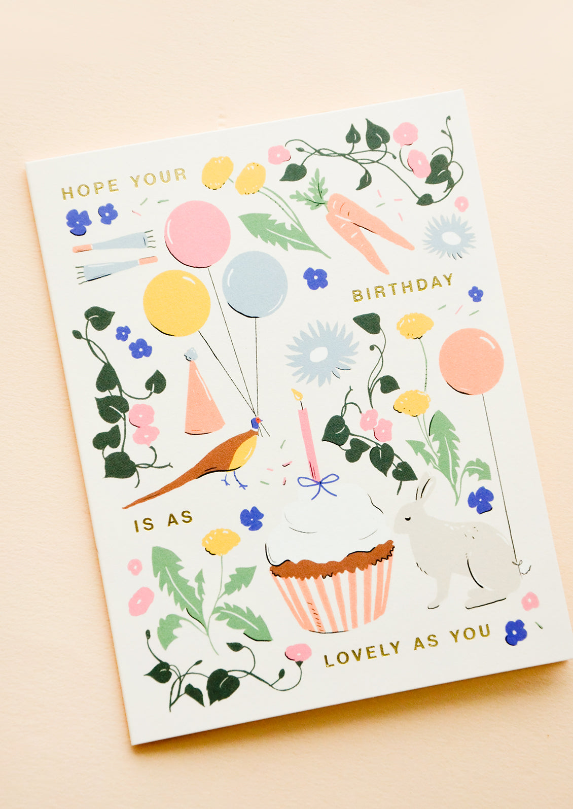 Whimsically illustrated greeting card with garden-centric scene and golden lettering reading "Hope your birthday is as lovely as you"