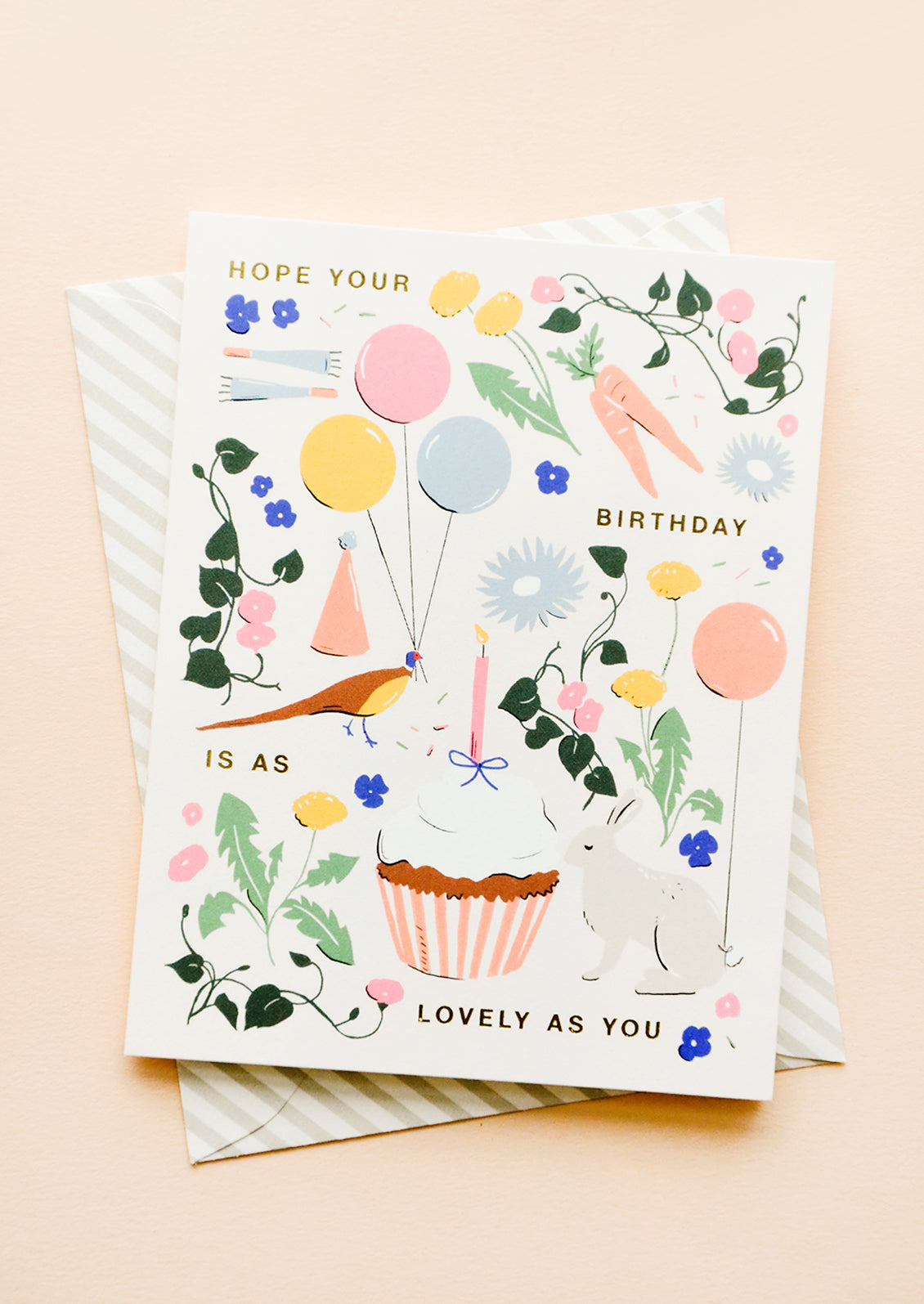 Whimsically illustrated greeting card with garden-centric scene and golden lettering reading "Hope your birthday is as lovely as you"