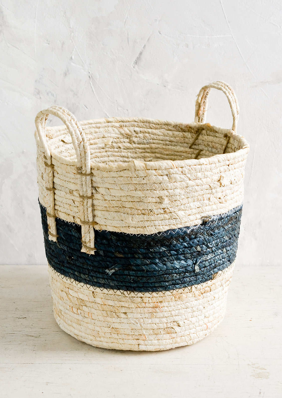 A storage basket with two top handles, woven from natural fiber.