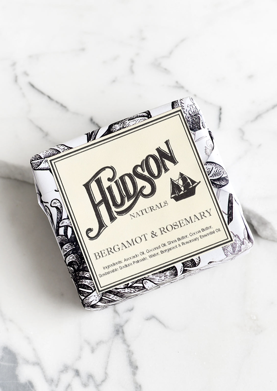 A square bar of soap in botanical printed packaging in Bergamot & Rosemary scent.