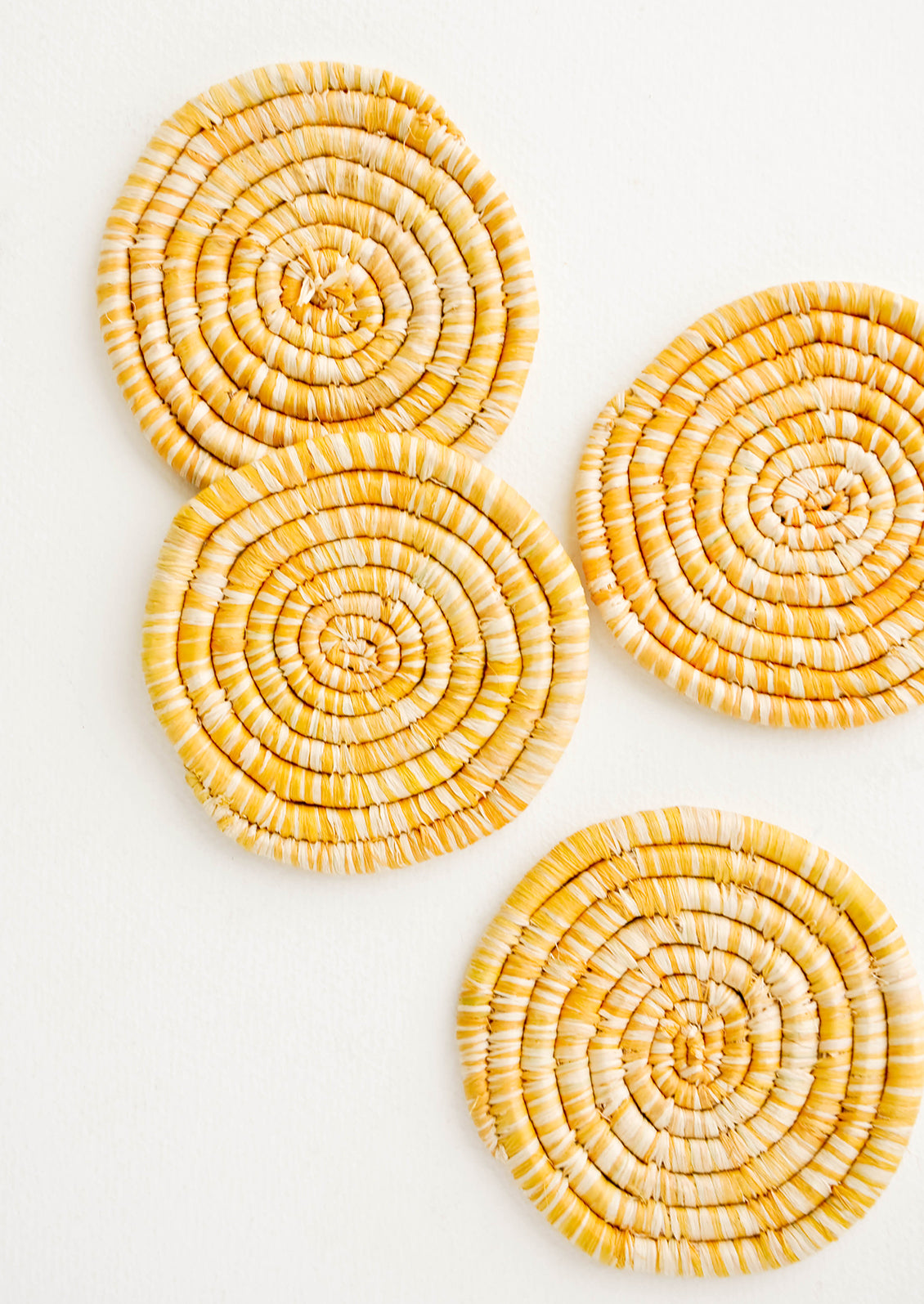 Set of 4 Round Woven Raffia Coasters in Yellow and natural stripe.