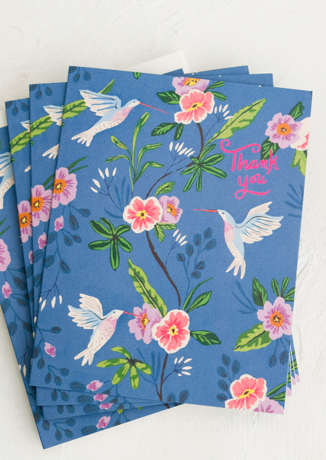 A set of blue greeting cards with hummingbird floral print, pink script at corner reads "Thank you".