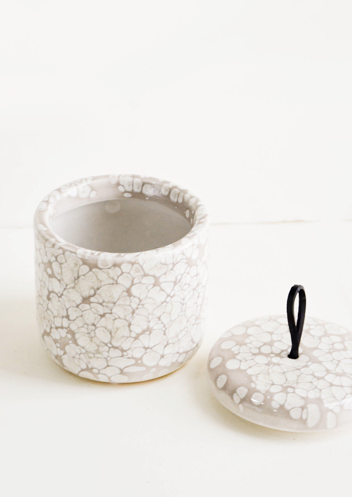 Ceramic storage jar in bubbly, glossy grey glaze with black leather pull on lid