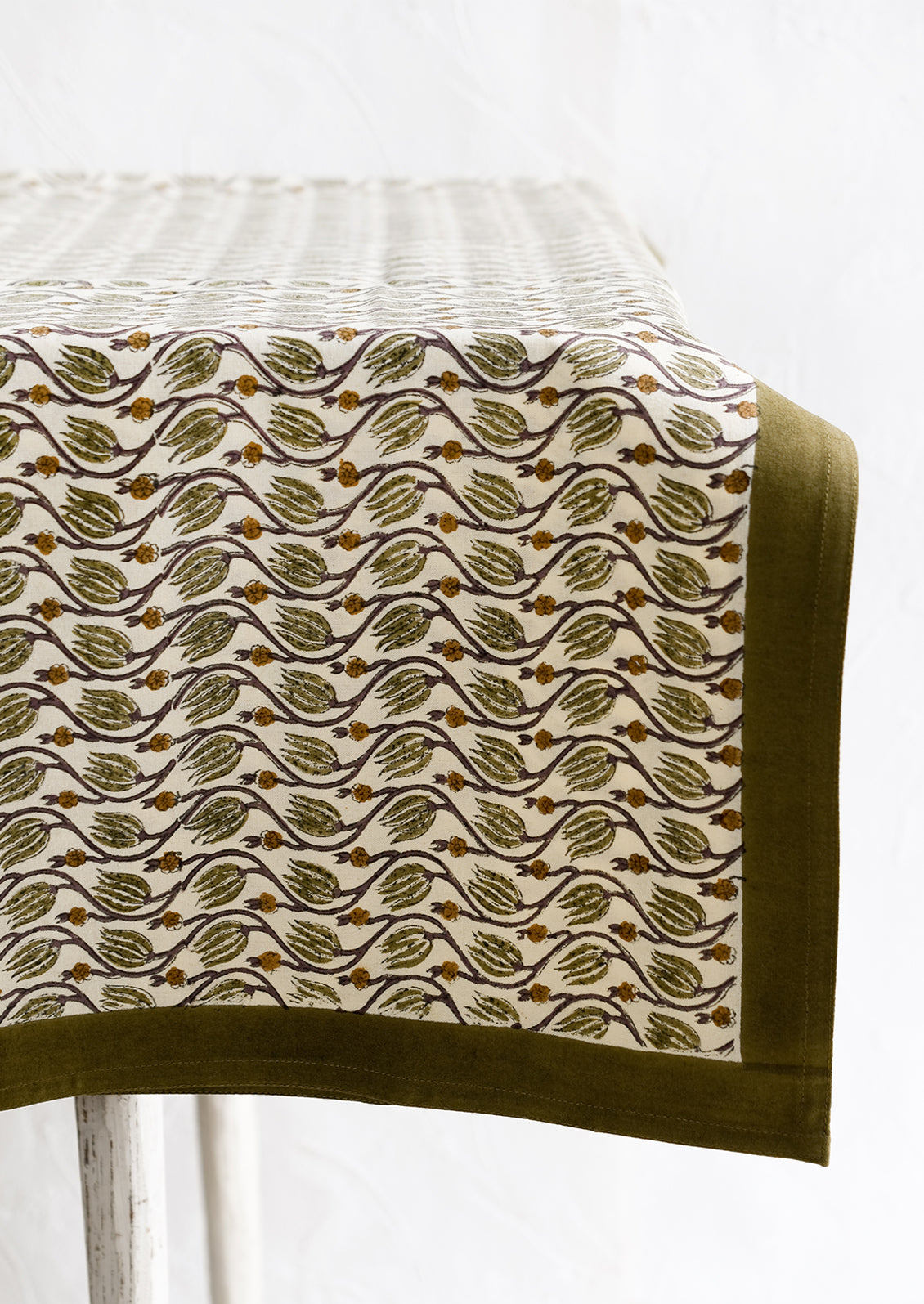 A botanical print tablecloth with olive green trim.