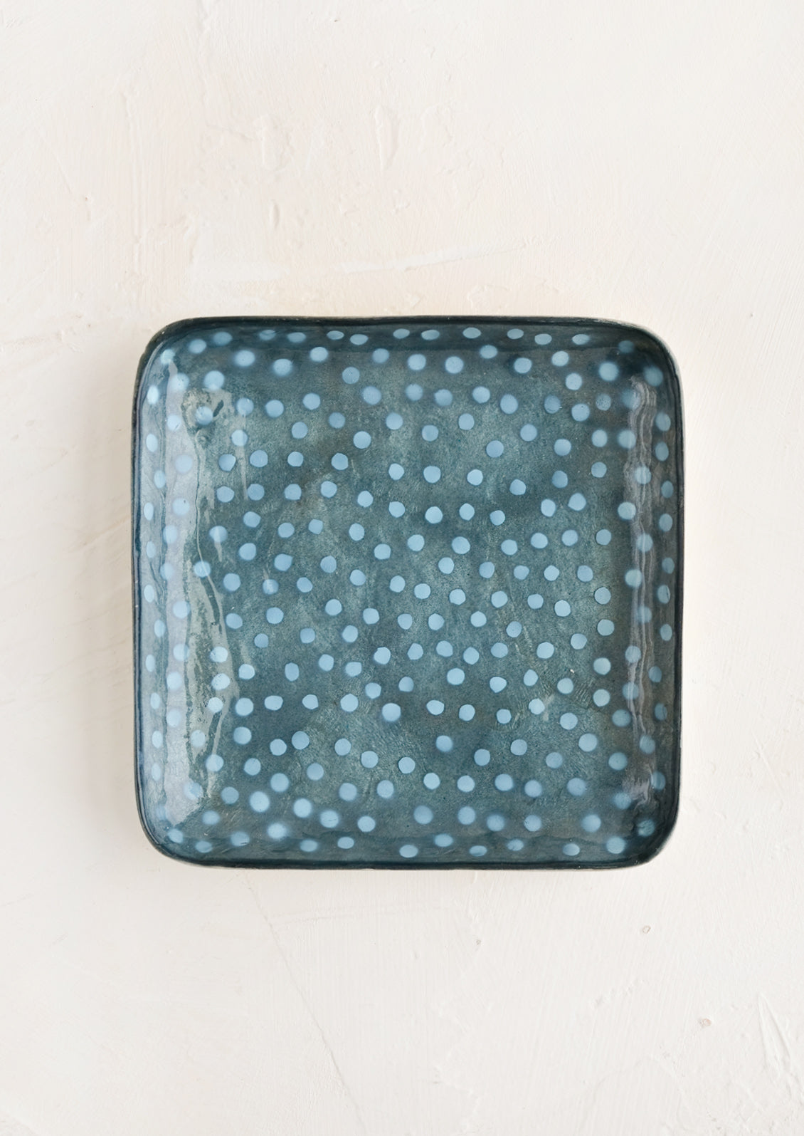 A small square catchall tray in indigo polka dot print.