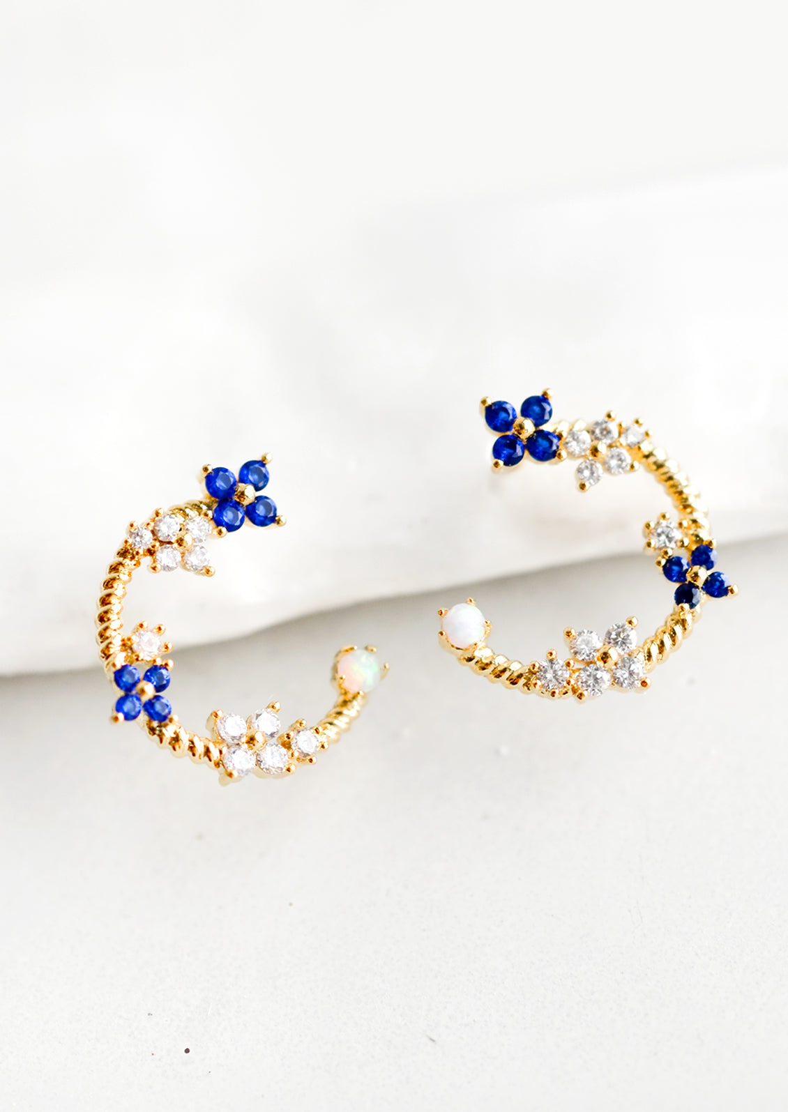 Gold hoop stud earrings with floral crystal detailing.