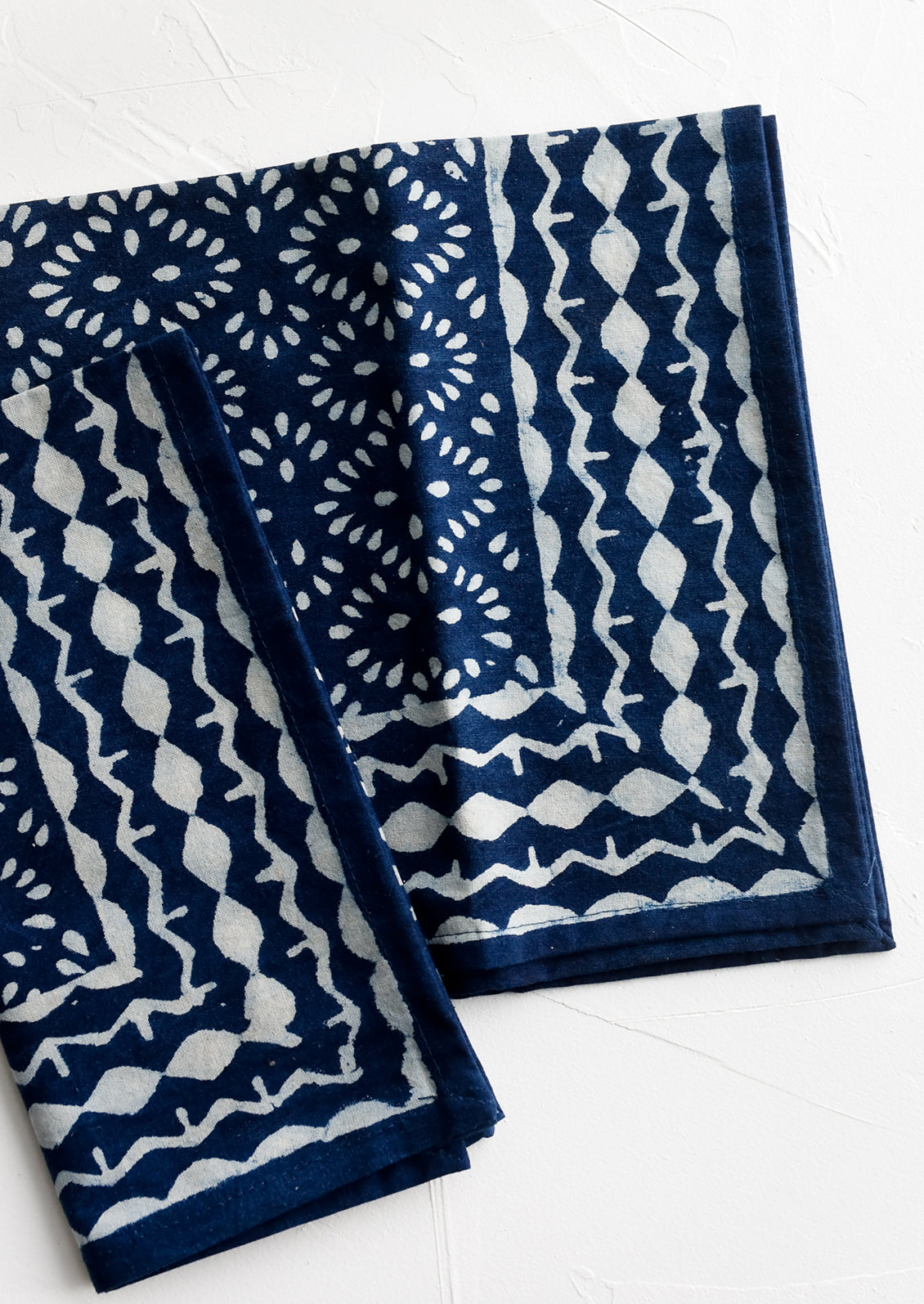 A pair of indigo napkins with white block printed pattern.