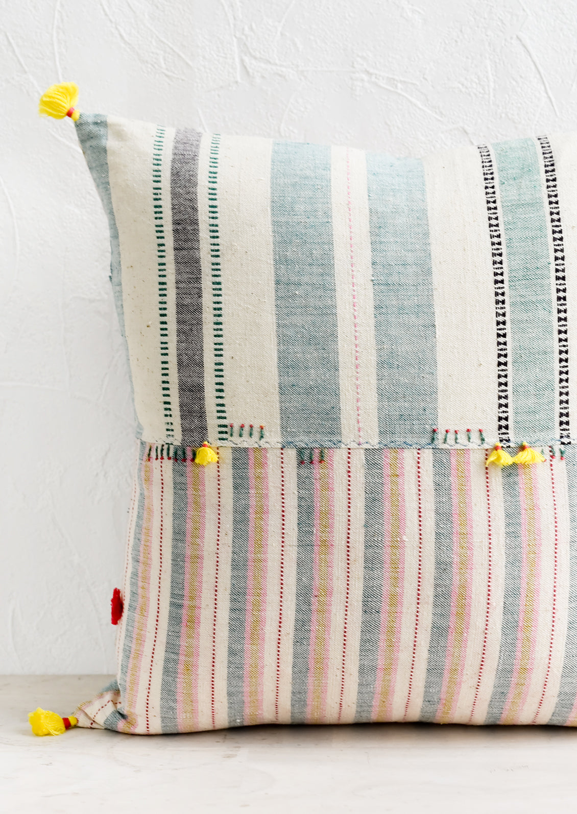 A cotton throw pillow in patchwork madras with pastel tassels.