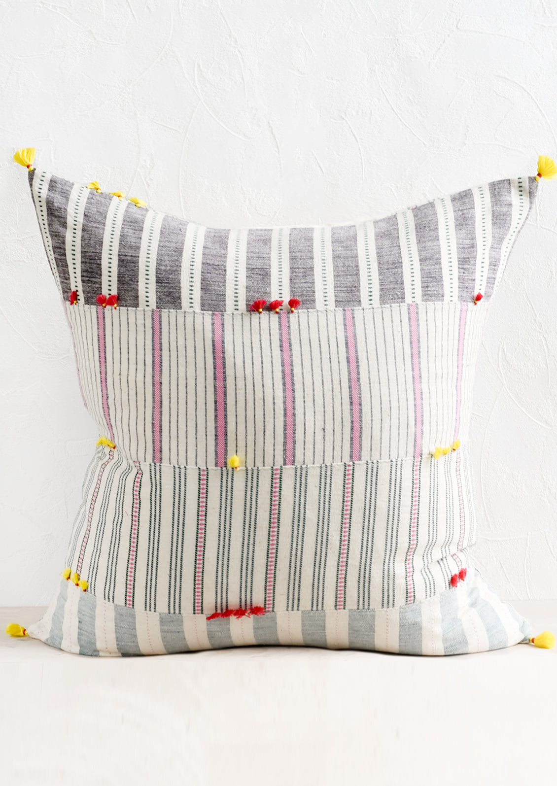 A cotton throw pillow in patchwork madras with pastel tassels.
