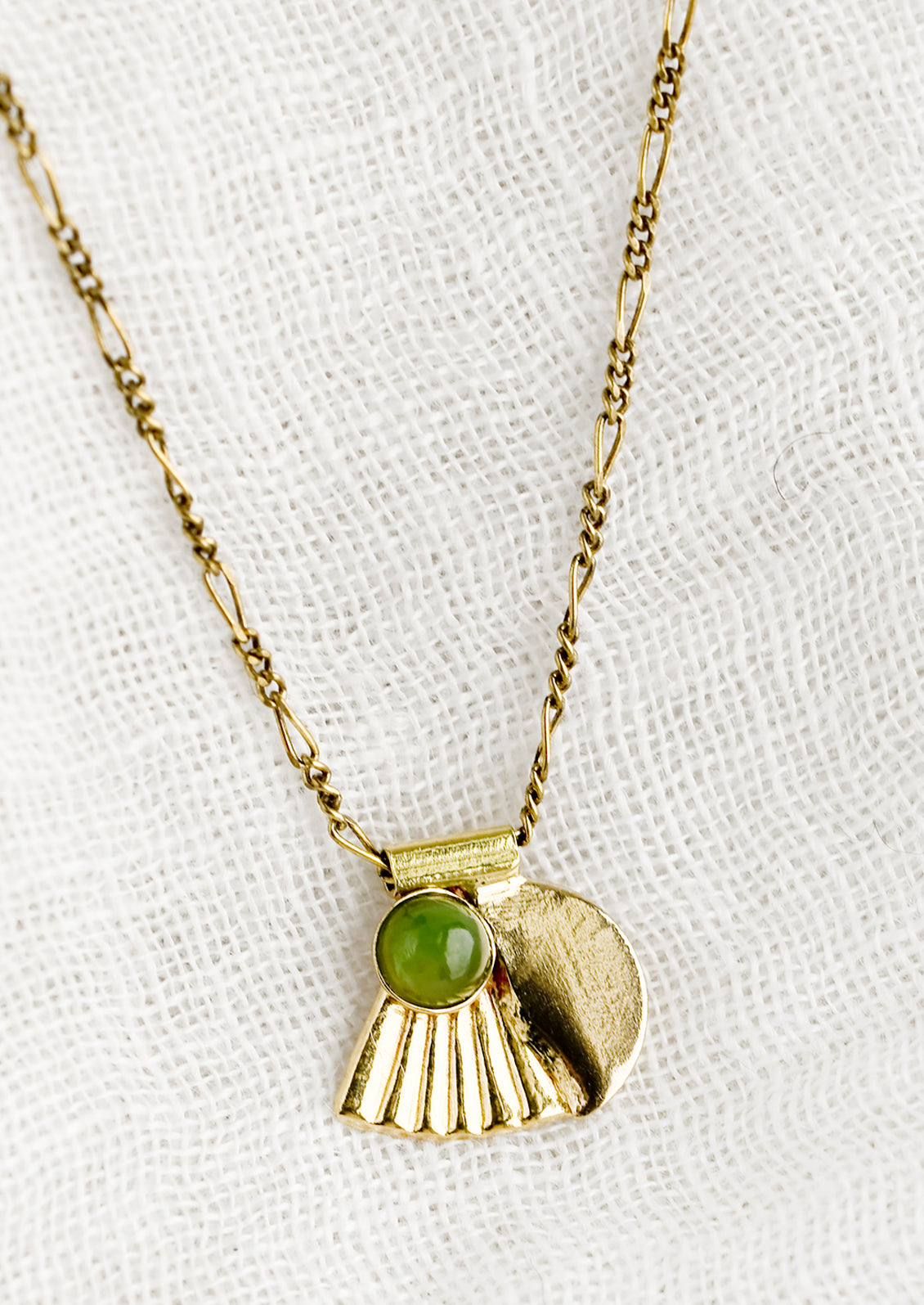 A neckace with art-deco style charm and jade bezel detail.