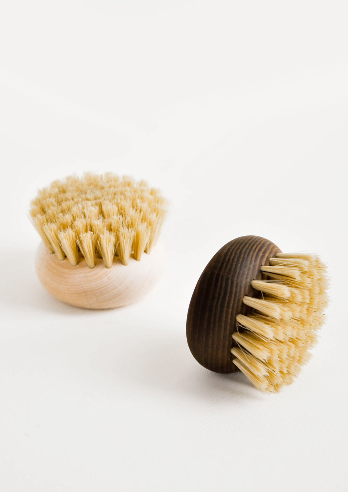 Two circular body brushes in light and dark natural woods. 
