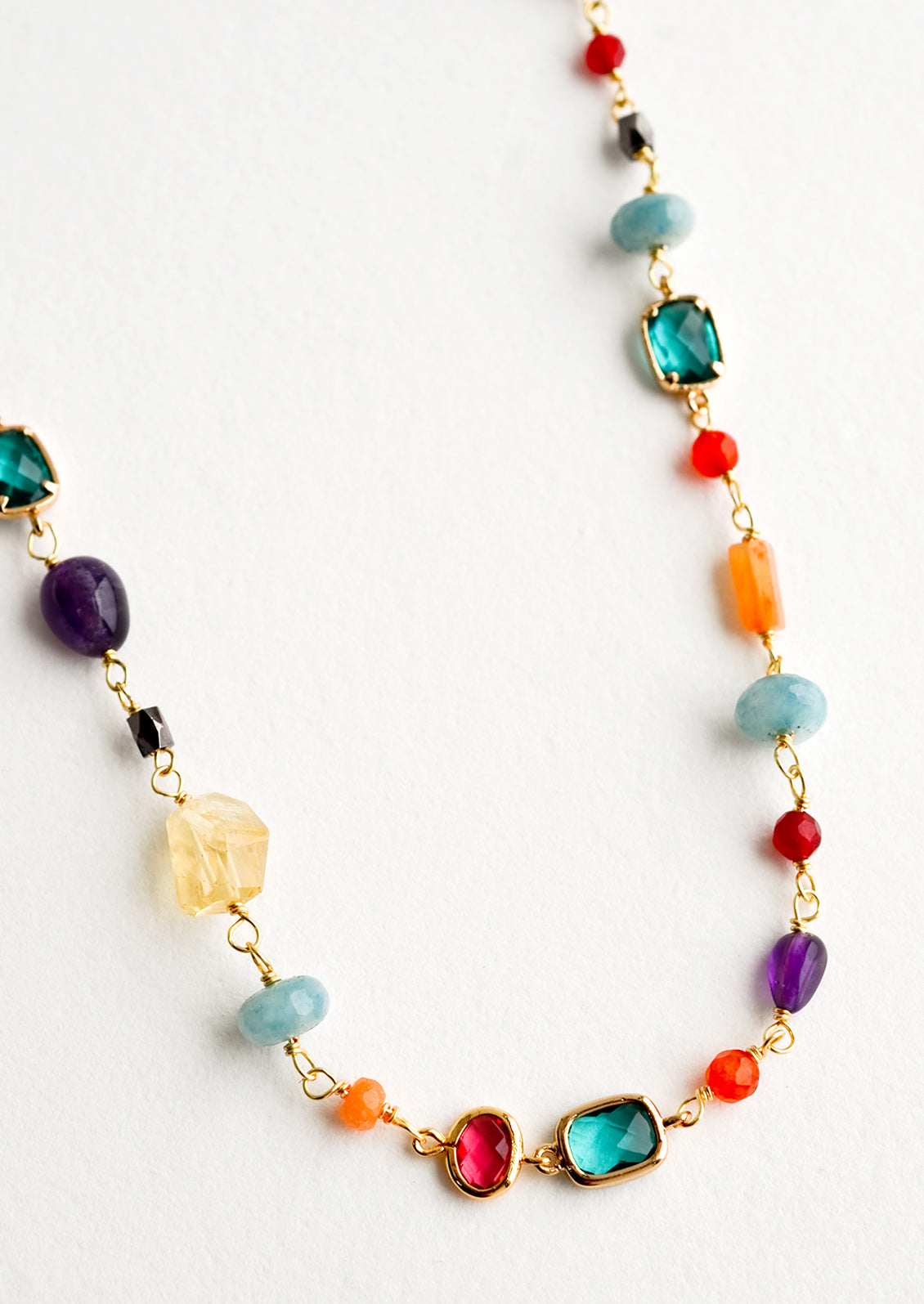 A necklace with individual, multicolor gemstone stations in a mix of shapes and sizes.