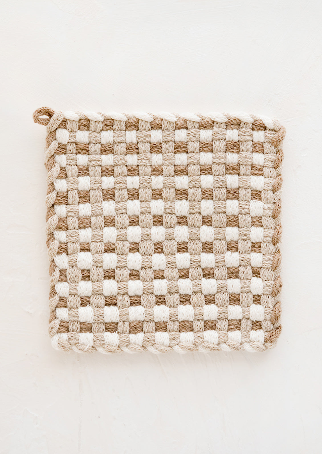 A hand-knit potholder in checkered weave of ivory, taupe and tan..