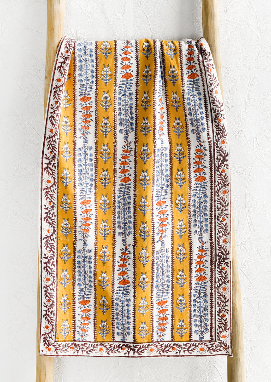 A stripe floral print table runner in marigold, purple and blue.