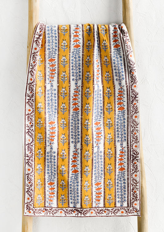 A stripe floral print table runner in marigold, purple and blue.