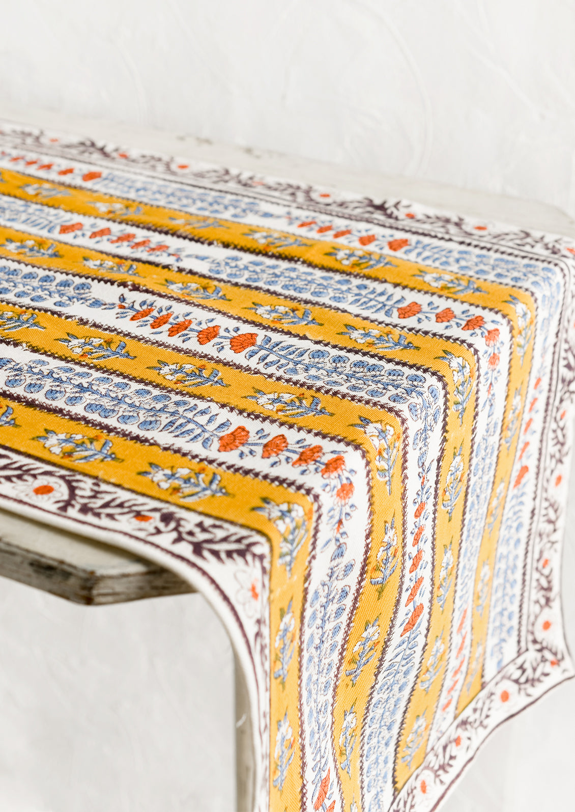 A stripe floral print table runner in marigold, purple and blue.