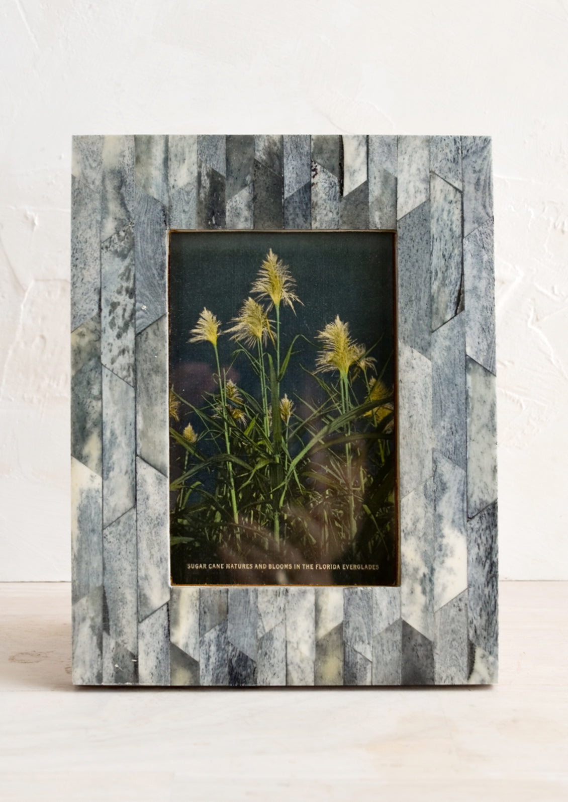 A bone picture frame with inlaid interlocking pattern in textured grey.