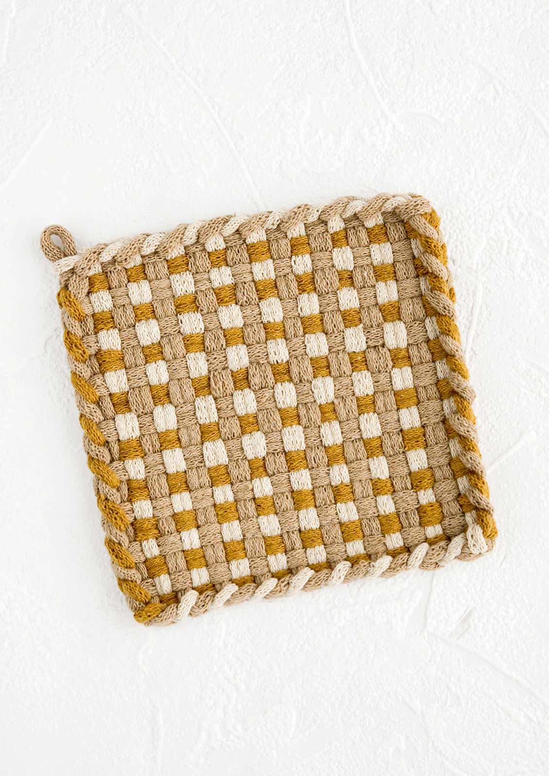 A hand-knit potholder in checkered weave of ochre, taupe and natural.