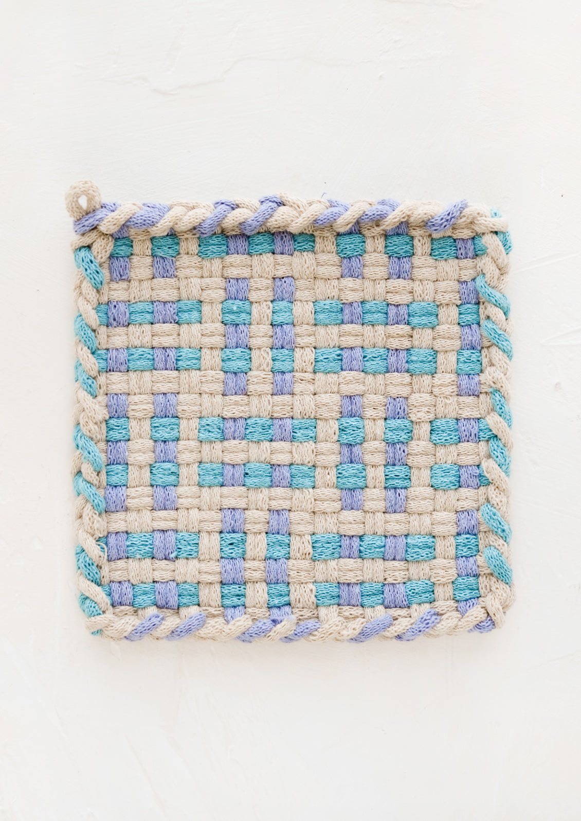 A hand-knit potholder in blue and turquoise woven pattern.