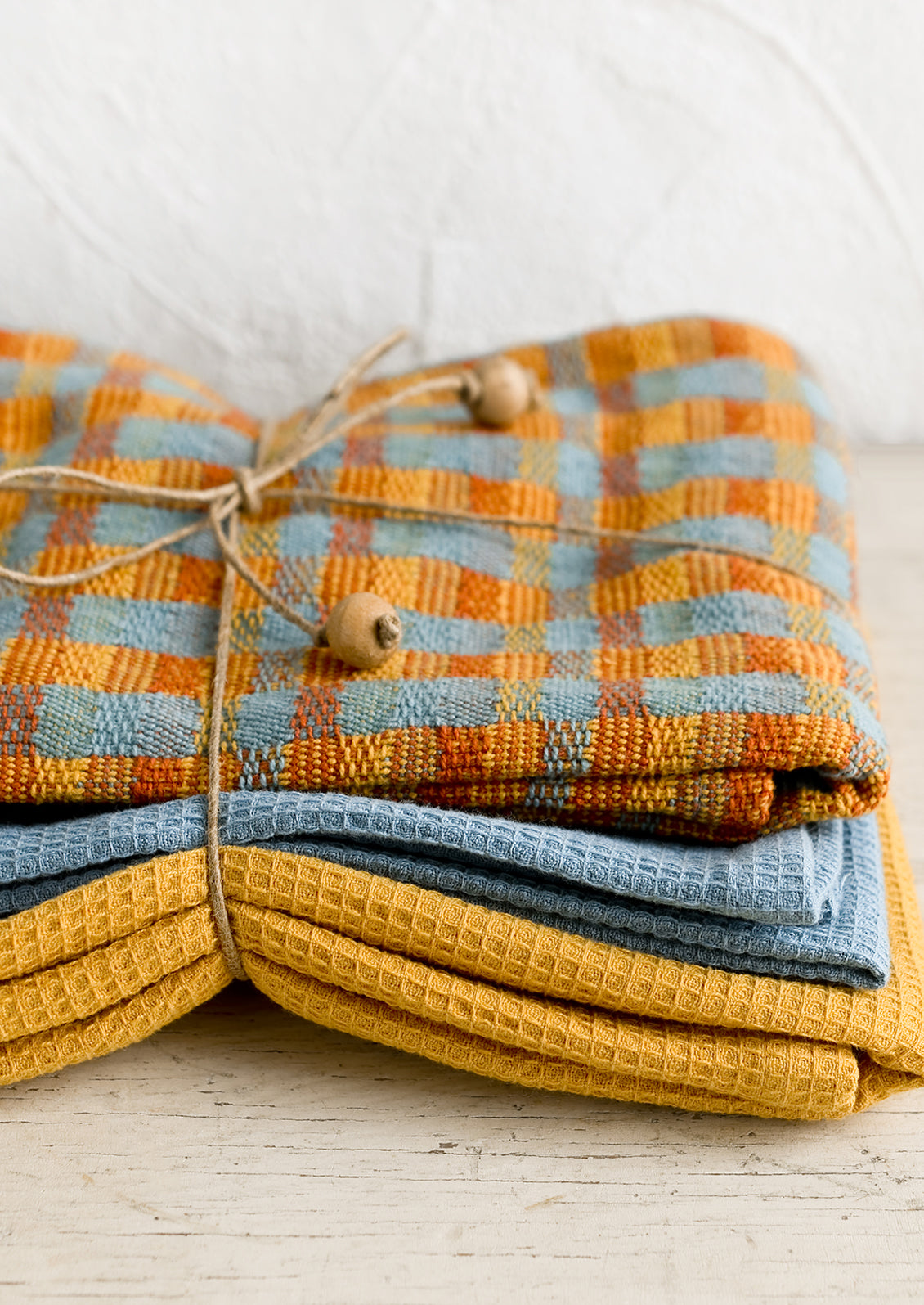 A set of three twine tied tea towels, one patterned two plain.