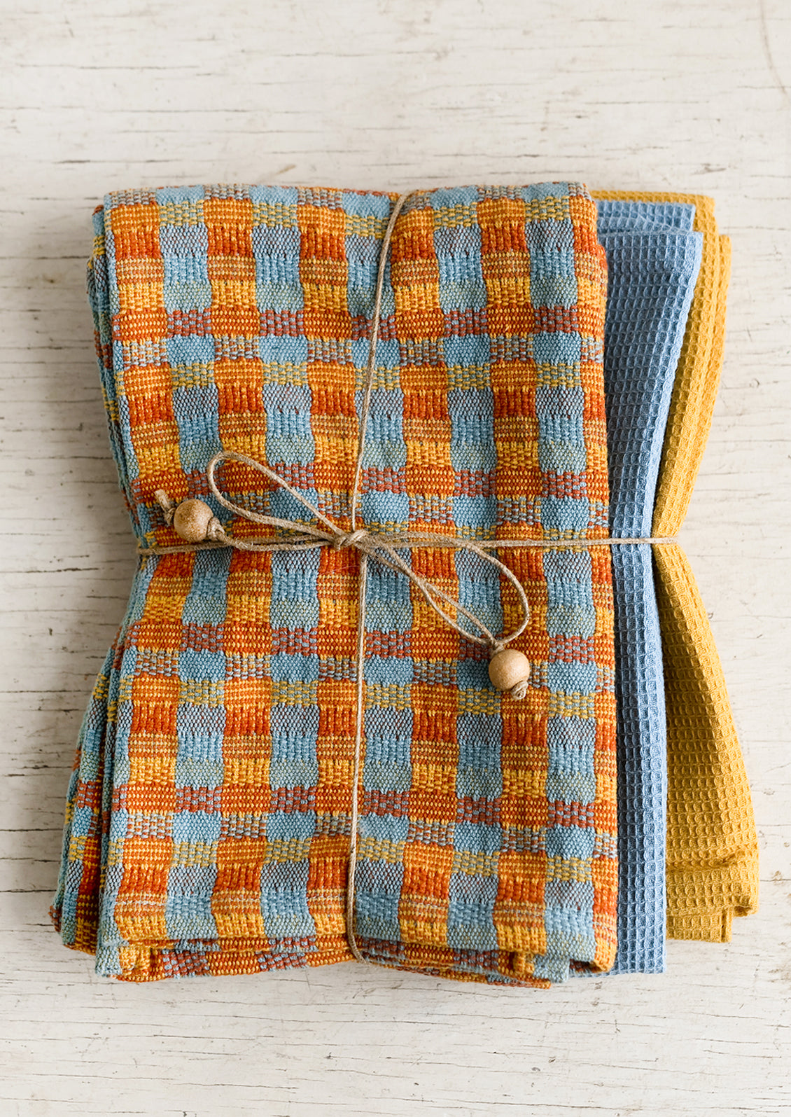 A set of three twine tied tea towels, one patterned two plain.