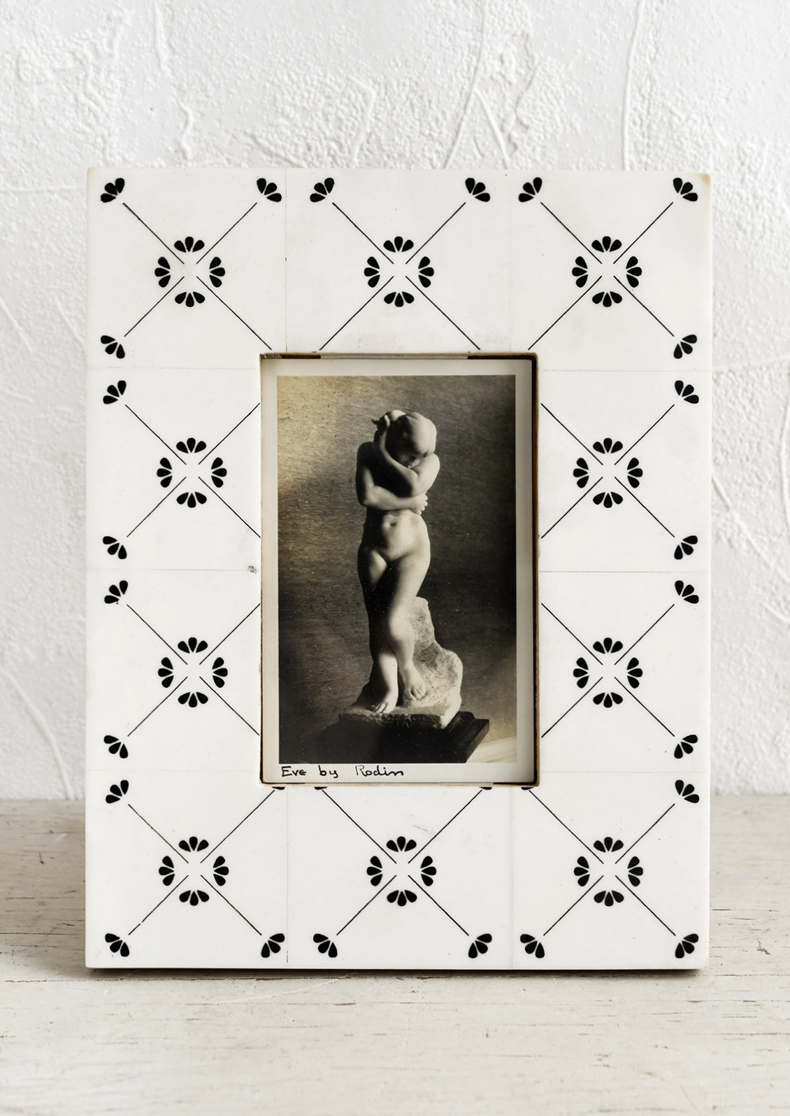 A picture frame made to look like white tile with black motif.