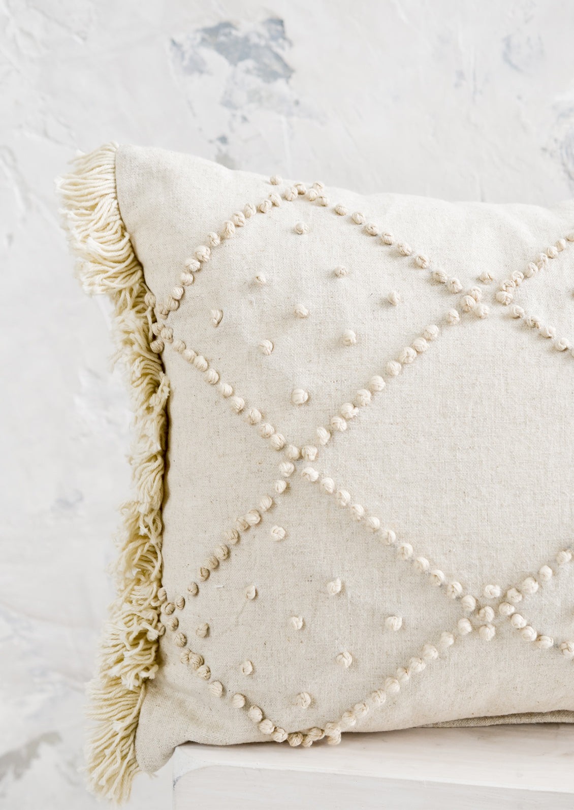 Knotted detailing on a linen lumbar pillow.