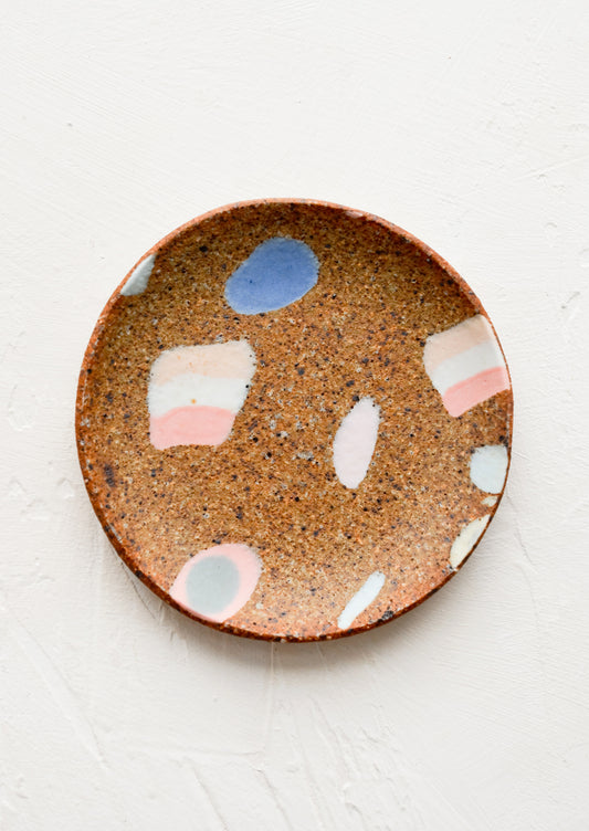 A round ceramic trinket dish with various inlay shapes.