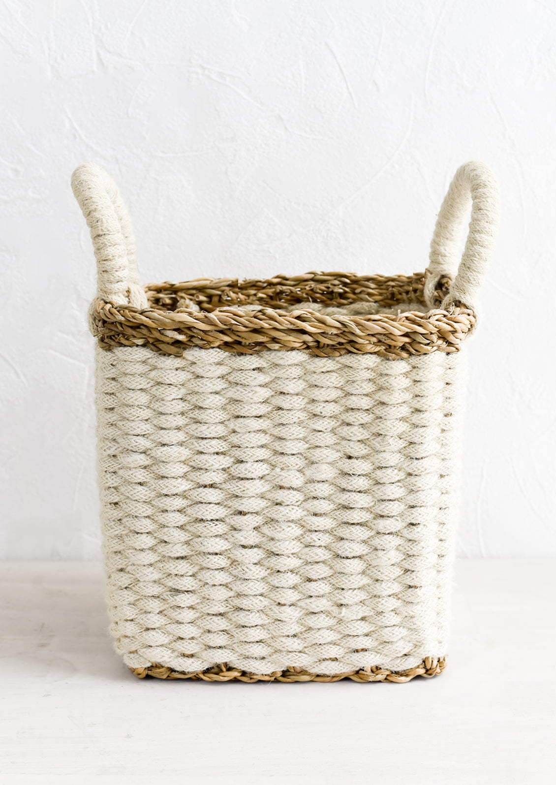 A square storage basket in woven straw and jute, small size.
