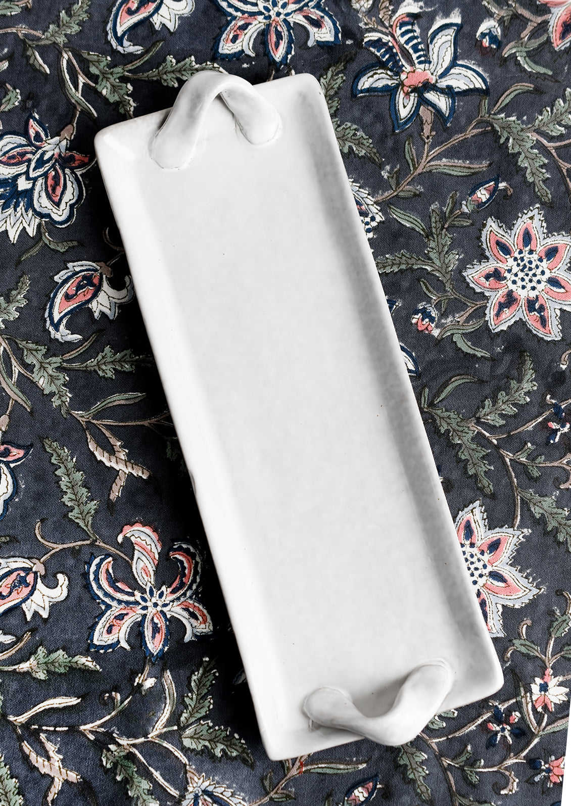 Long and skinny ceramic tray with side handle detail.