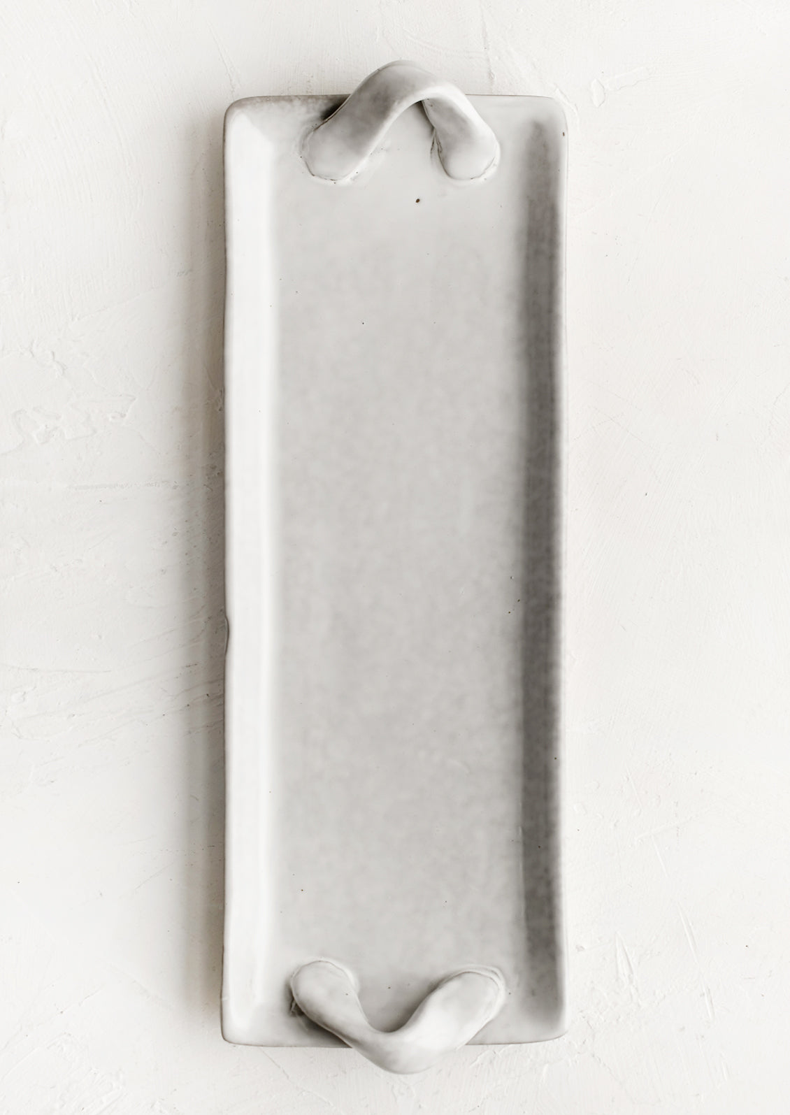 Long and skinny ceramic tray with side handle detail.