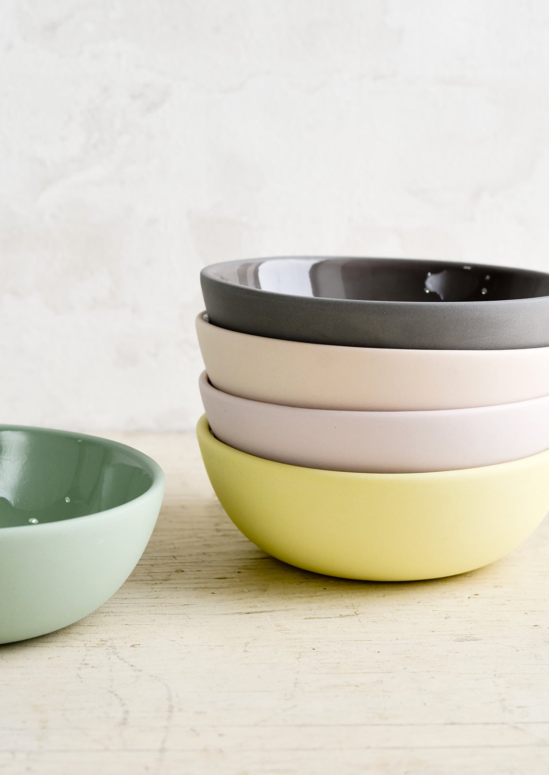 A stack of bowls with matte exterior and glossy interior in assorted pastel hues.