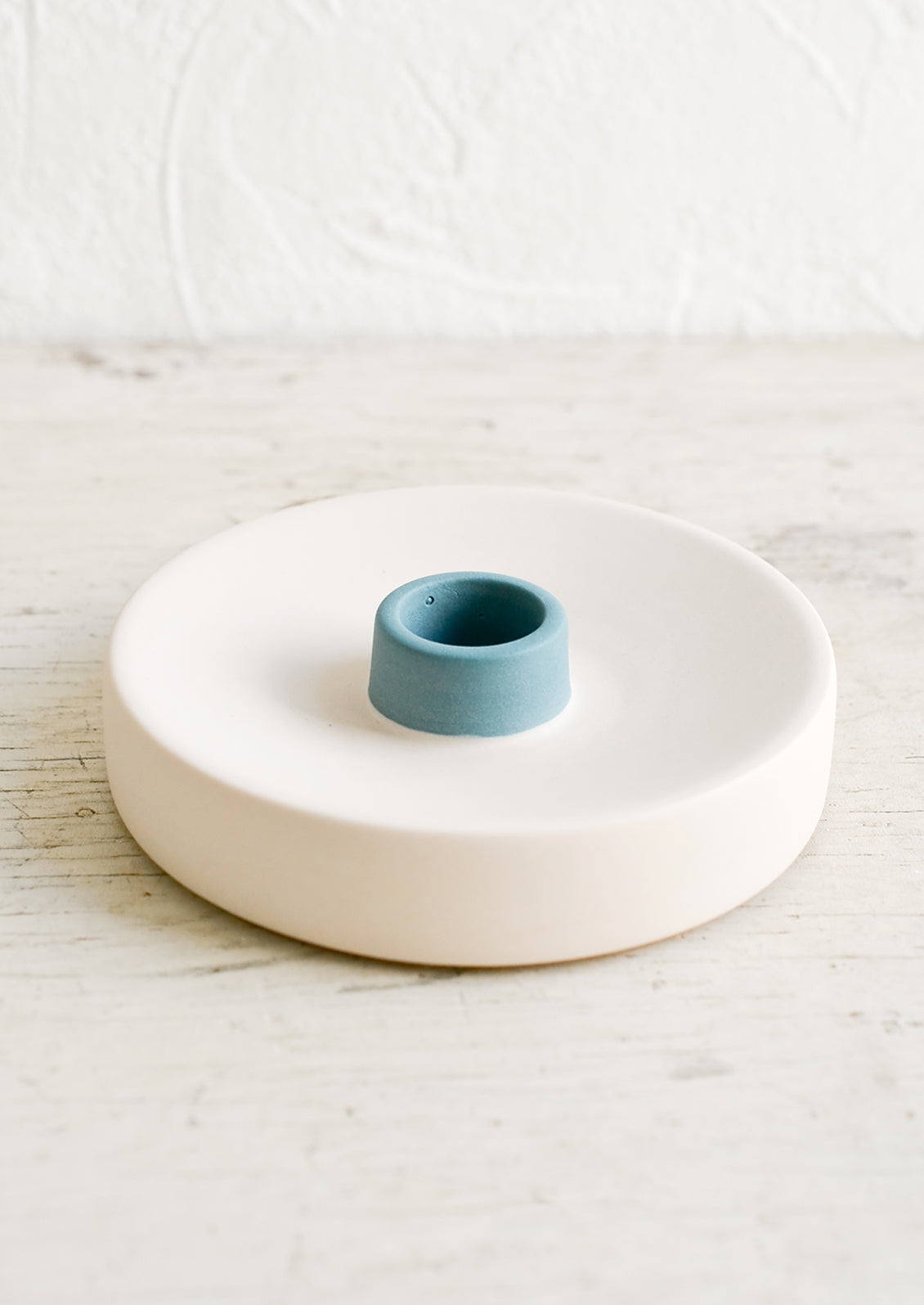 A round ceramic taper candle holder in nude and blue.