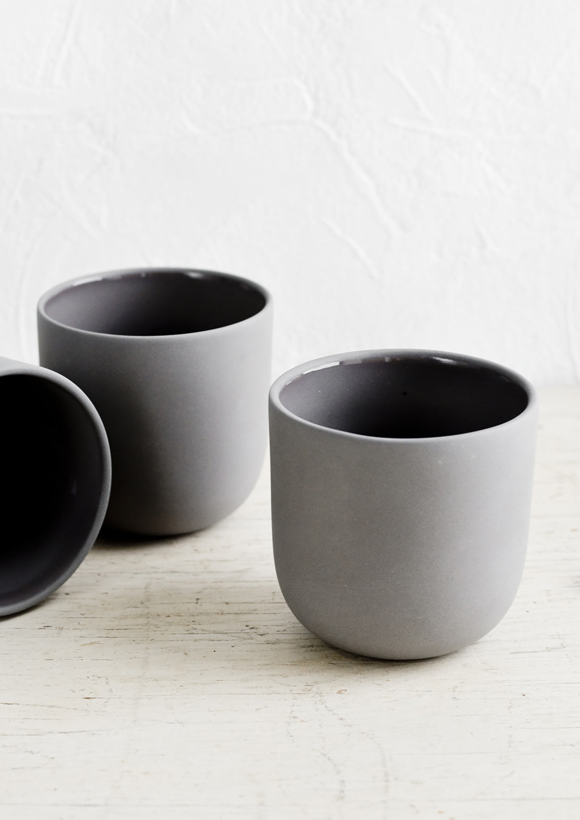 Three dark grey matte porcelain short tumblers.