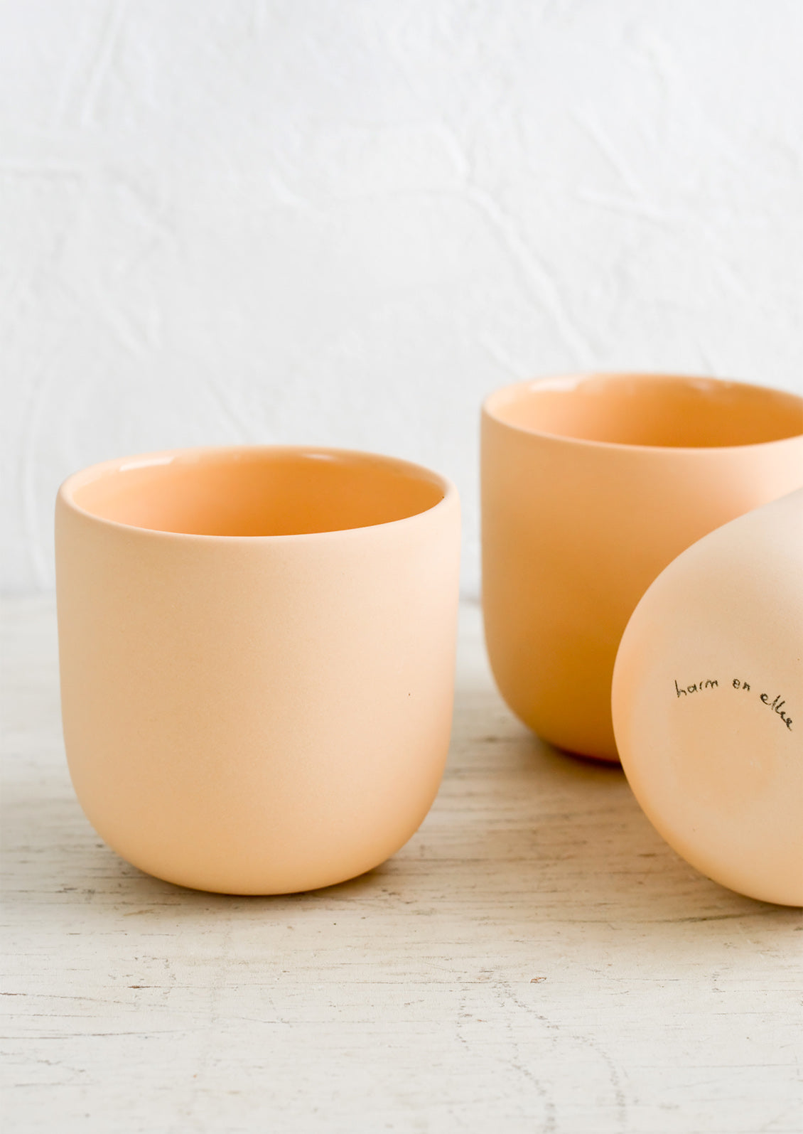 Three orange matte porcelain short tumblers.