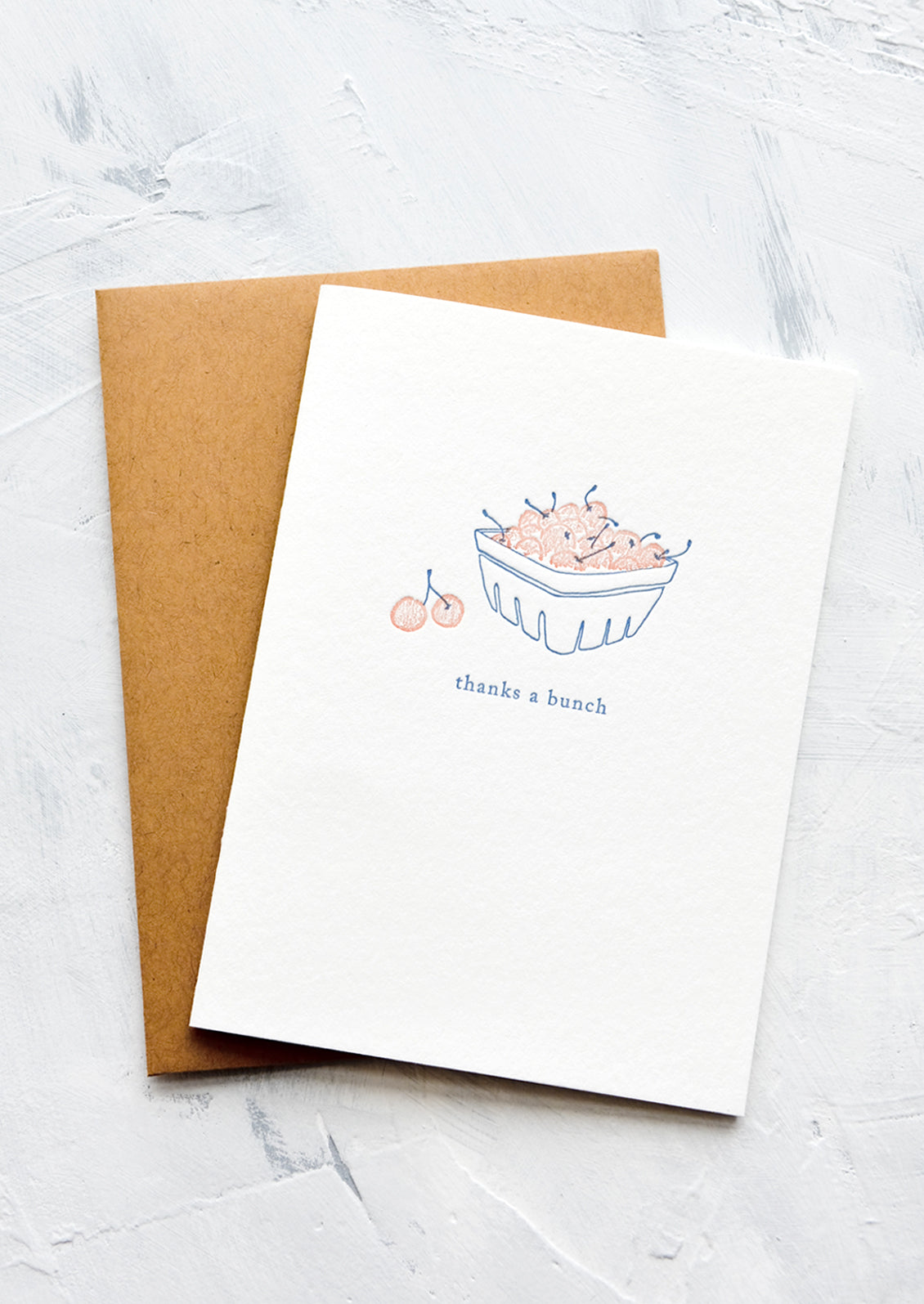 A letterpress printed greeting card with an image of cherries in a berry basket with text below reading "thanks a bunch".