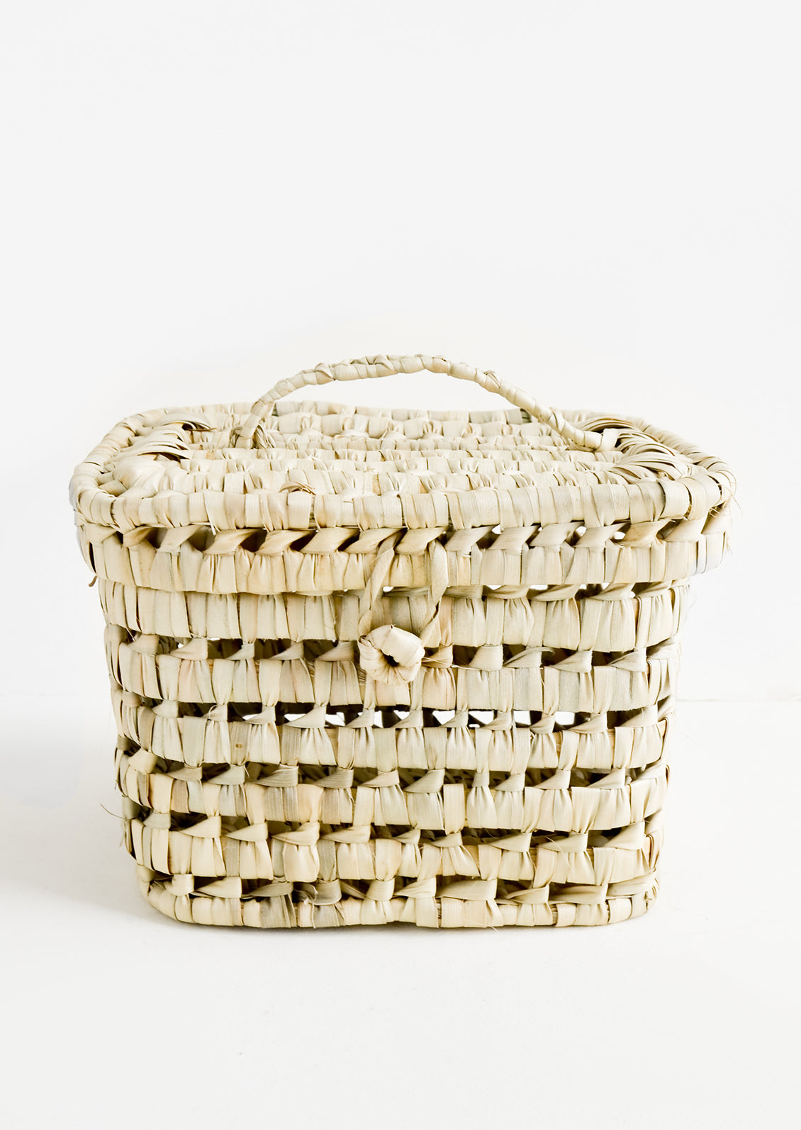 A square-shaped, lidded basket made from woven natural palm leaf.