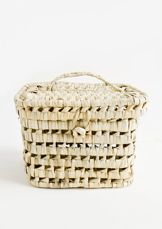 A square-shaped, lidded basket made from woven natural palm leaf.