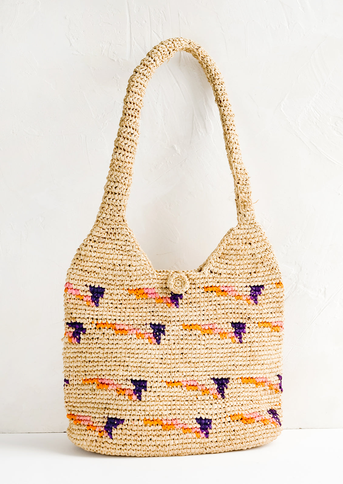 A hobo tote made from natural raffia with pink, purple and orange detailing.