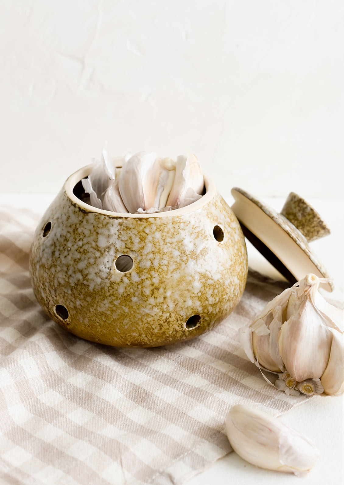 A brown ceramic garlic keeper with garlic heads.