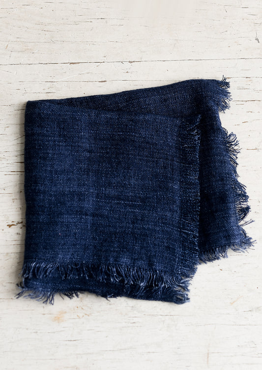 A folded navy blue linen napkin with frayed edges.