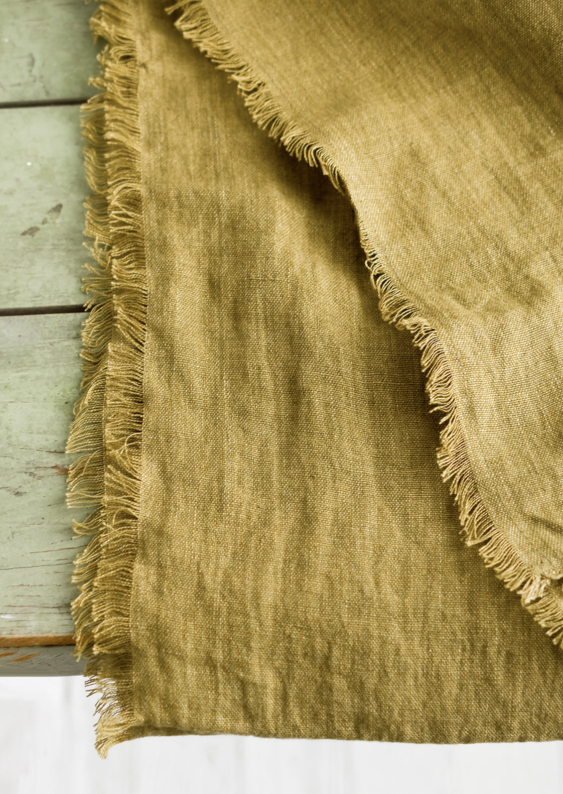 A frayed edge linen table runner in ochre.