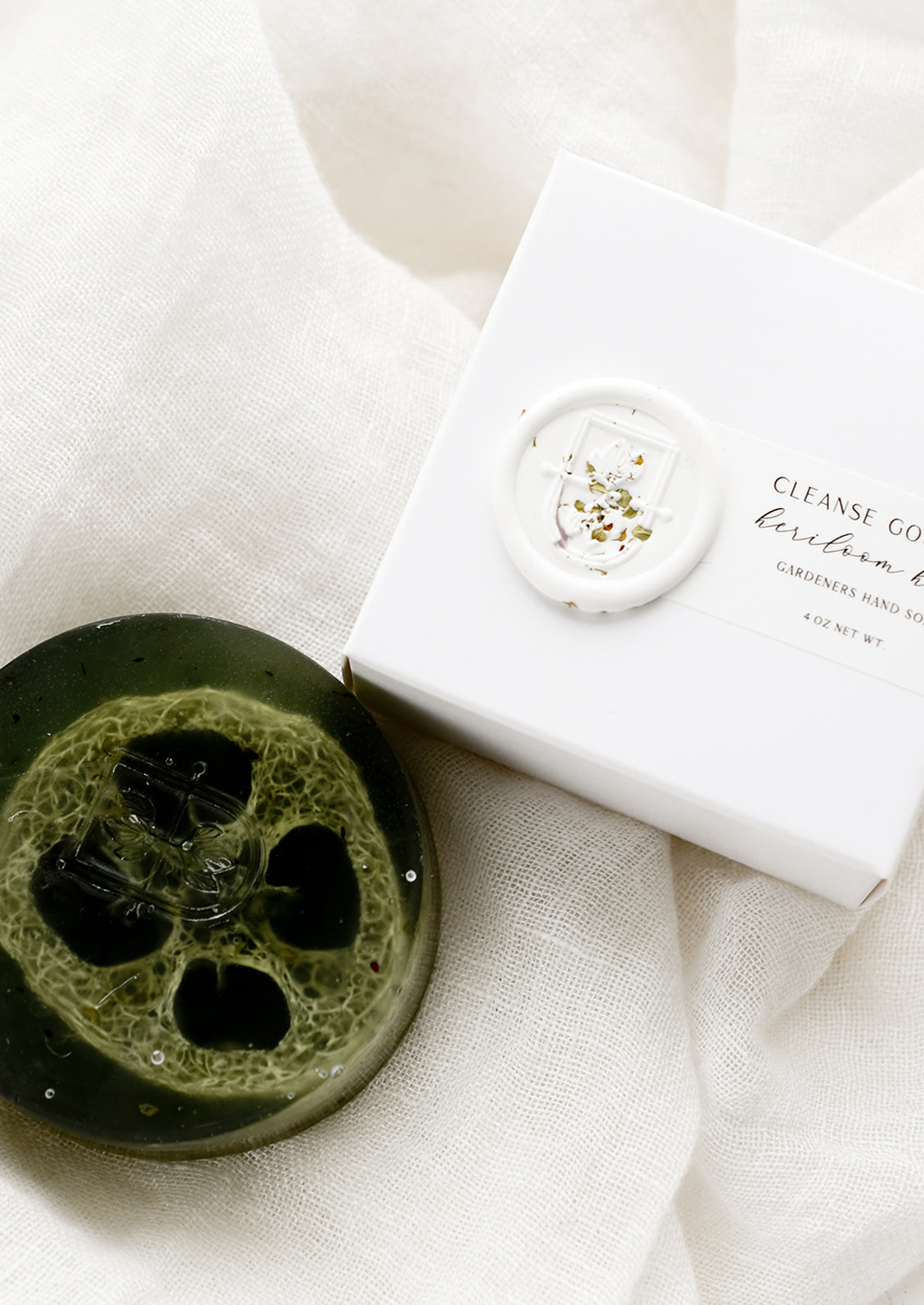 A round translucent green bar soap with wax seal packaging.