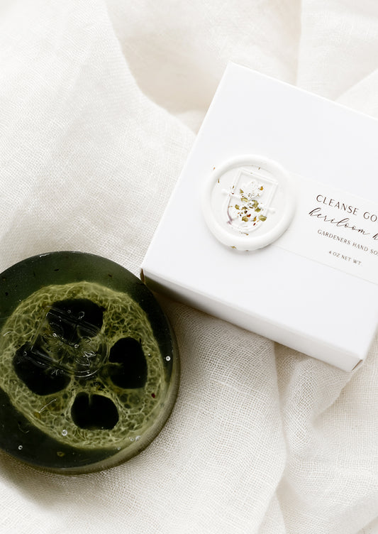A round translucent green bar soap with wax seal packaging.